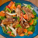a plate of roasted meat and chopped mixed vegetables