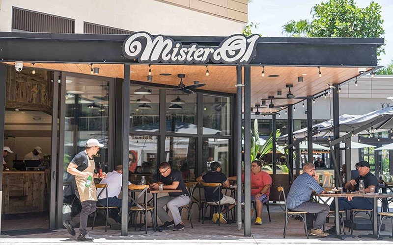 Mister 01 Pizza outdoor sign in Coconut Grove, FL. There are people sitting in the outdoor area.