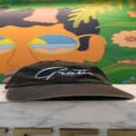 A black baseball hat with the “Grove” embroidered on the front, sitting on a marble counter in front of a colorful mural.