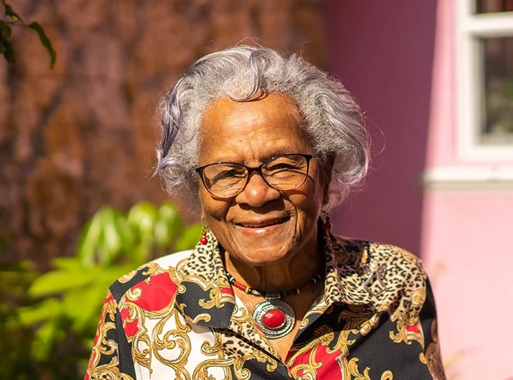 Elderly black woman with glasses and colorful silk blouse