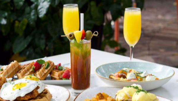 mimosas and waffles topped with eggs.