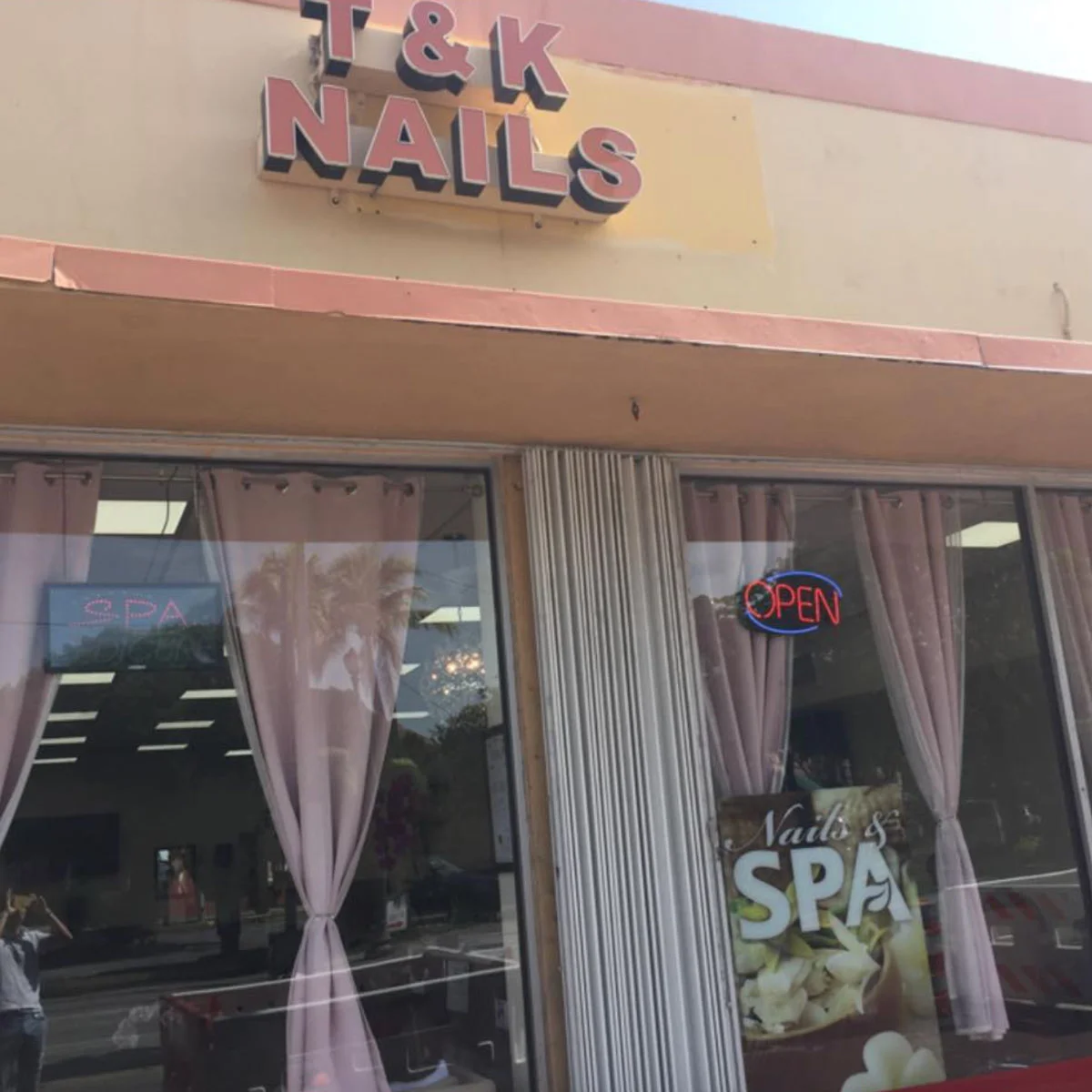 Exterior windows of T&K nails in Coconut Grove with an Open sign hanging up