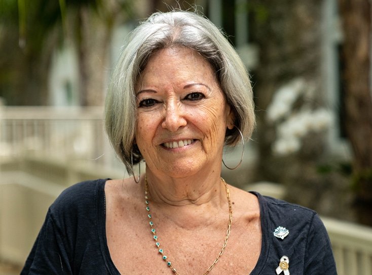 A lady with gray hair smiling wearing a black blouse.