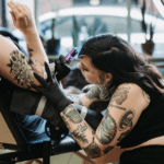 A woman tattooing a person’s arm.