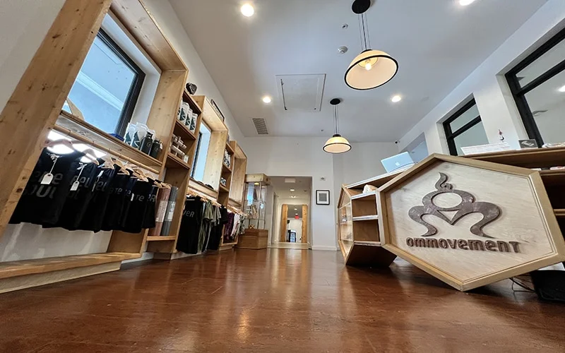 Inside of Om Movement, in Coconut Grove, FL. There is a desk and some clothing on display racks.