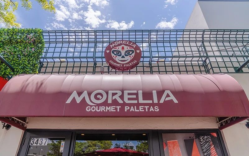 Morelia Gourmet Paletas exterior building red awning and greenery growing above the sign.