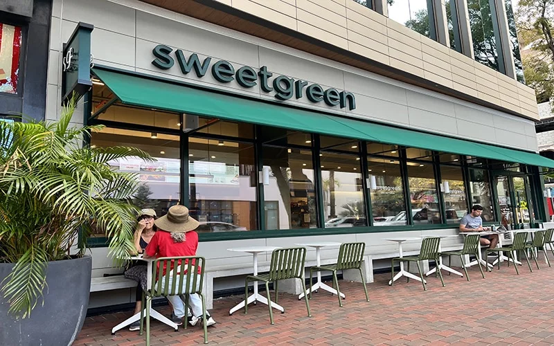 Exterior building of Sweetgreen Coconut Grove with people sitting at the tables.
