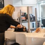 Person washing another person’s hair at Ugo Di Roma Salon + Day Spa
