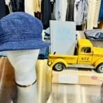 A table display with a mannequin head wearing a hat next to a yellow toy truck.