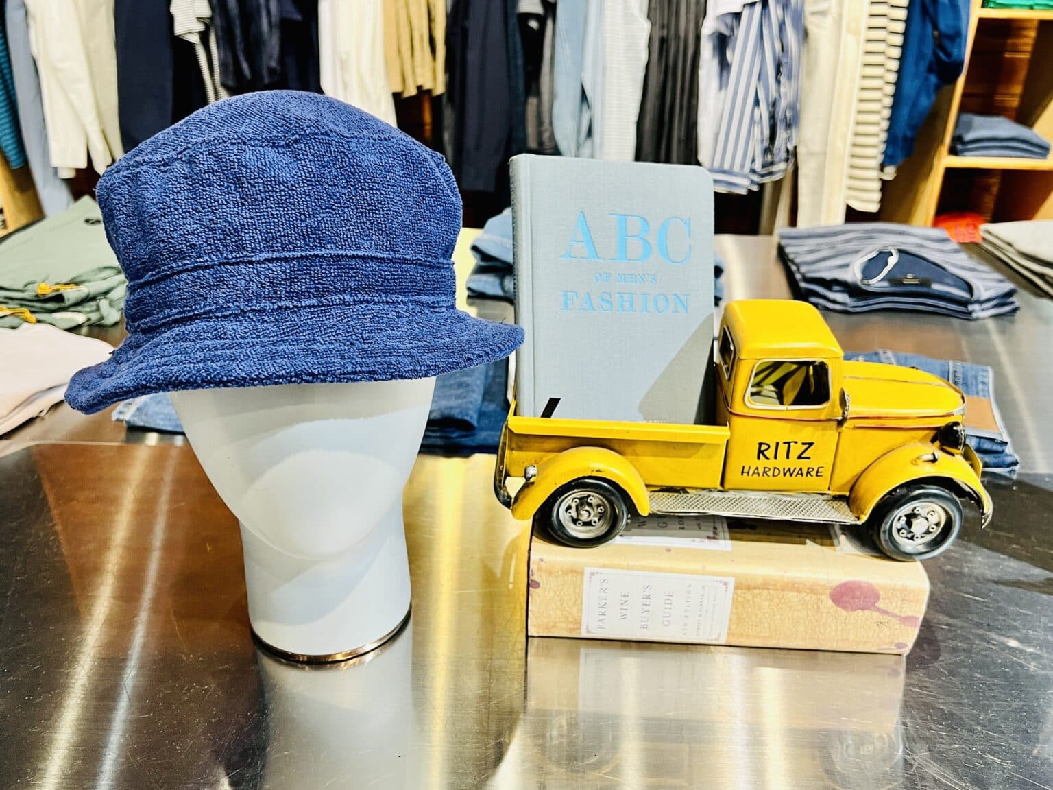 A table display with a mannequin head wearing a hat next to a yellow toy truck.