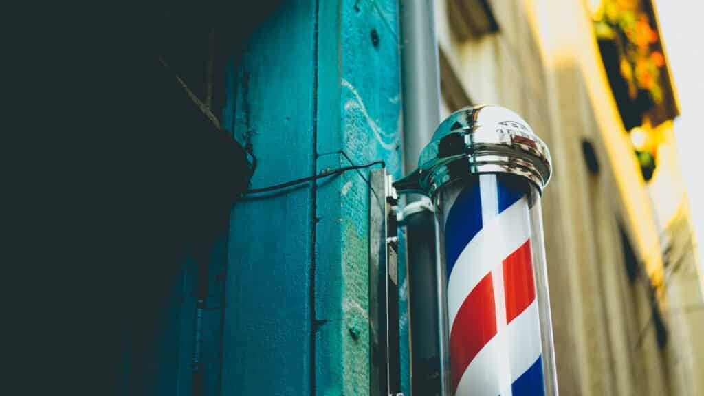 exterior of a blue building with an old fashioned barbershop pole with red, white and blue stripes.
