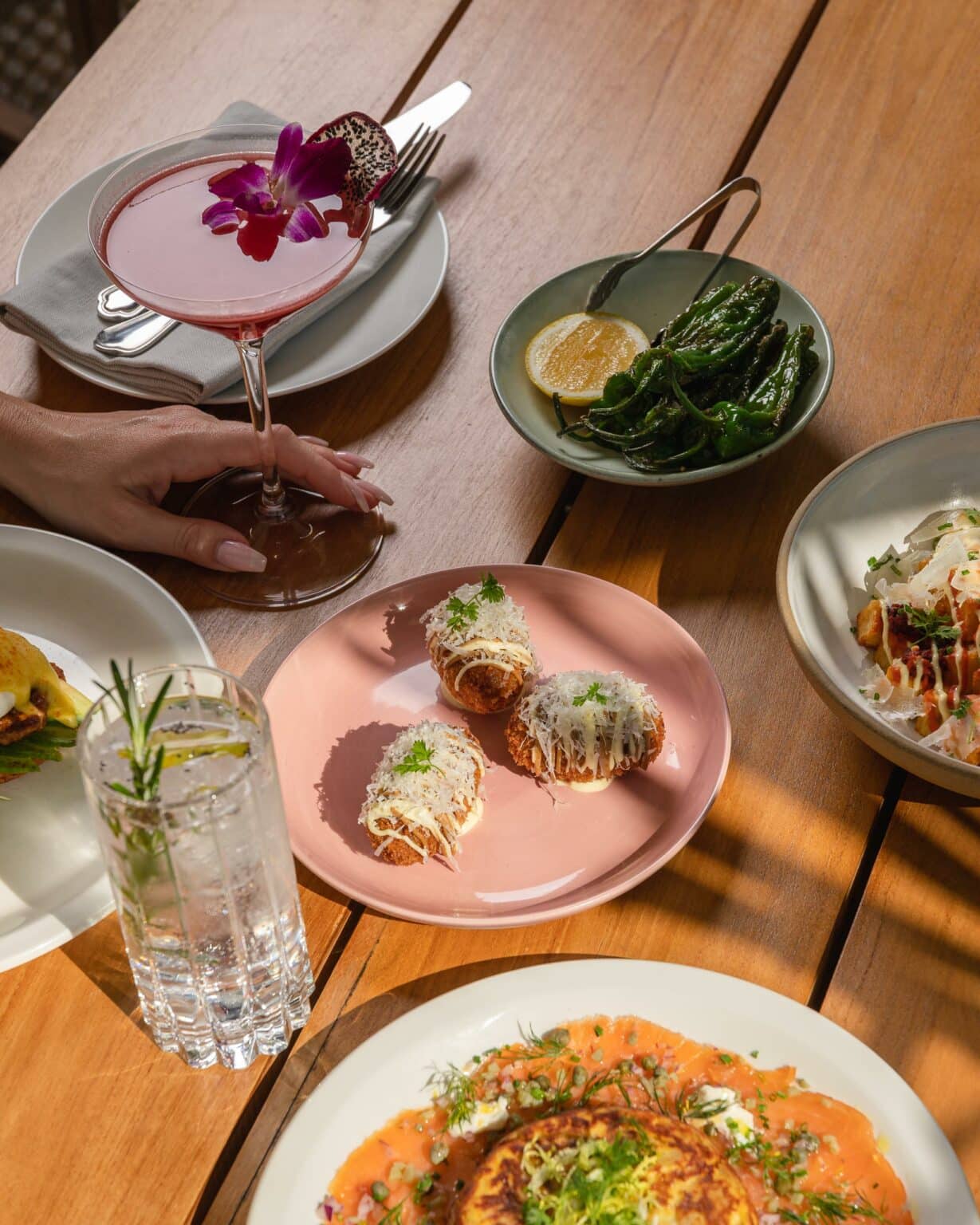A person holding a fancy drink next to a bunch of plated food options from Level 6 restaurant.