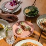 A person holding a fancy drink next to a bunch of plated food options from Level 6 restaurant.
