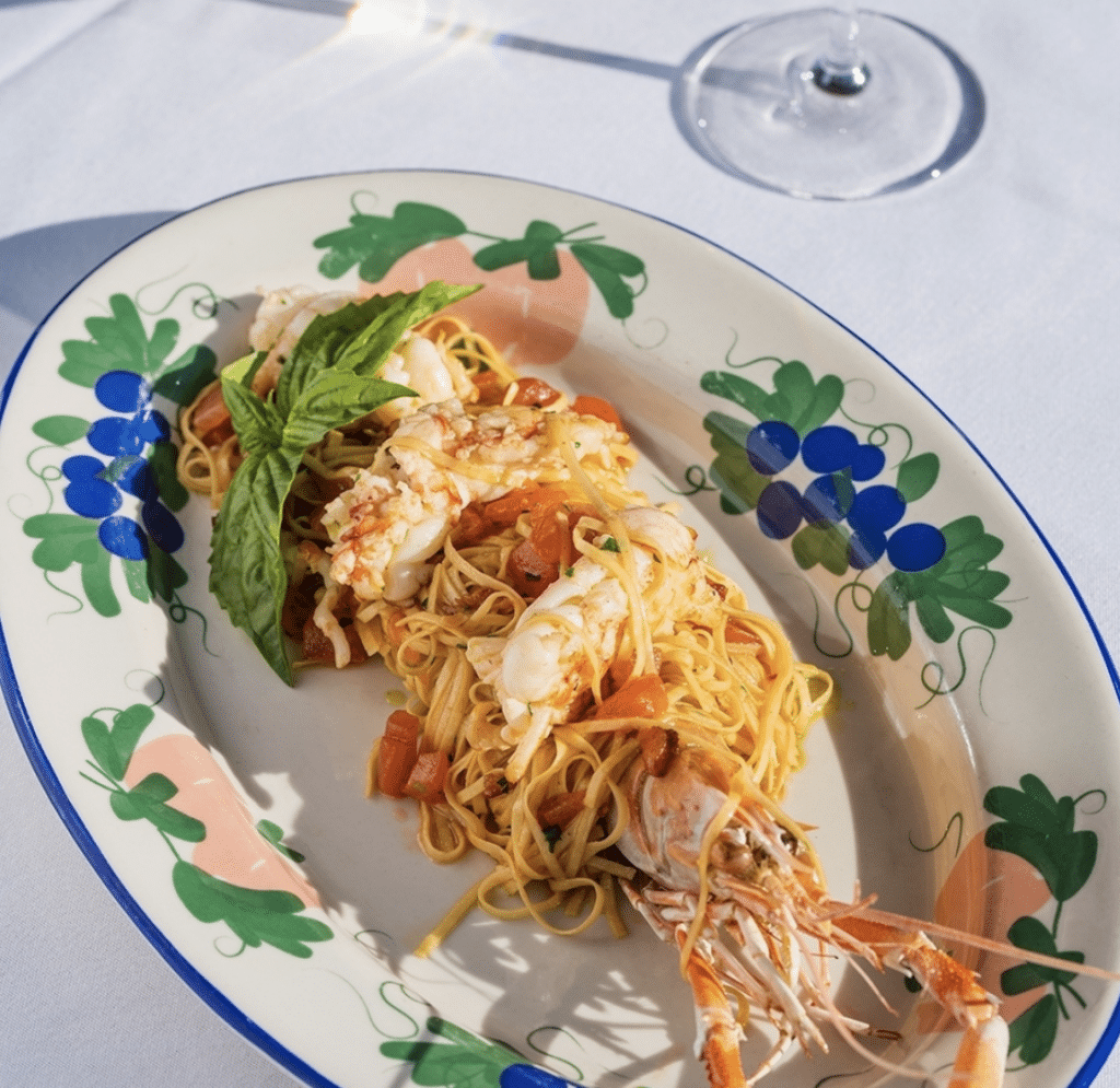 Fancy plated lobster cooked with pasta on a floral plate.