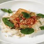 Cuban dish of food on a white plant with basil on top.