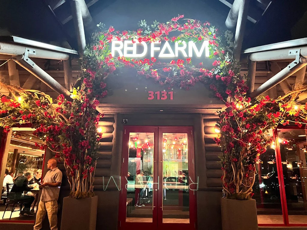 The exterior building of Red Farm restaurant with flowers trailing the archway.
