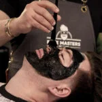 colorist applies black dye to man's facial hair