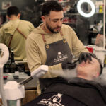 barber in fade masters apron trims a man's moustache