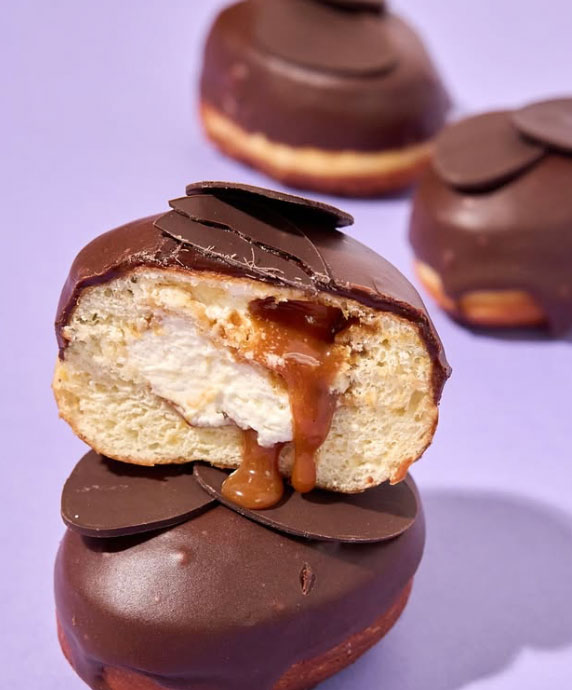 cut open donut filled with creme and Dulce de leche and topped with chocolate