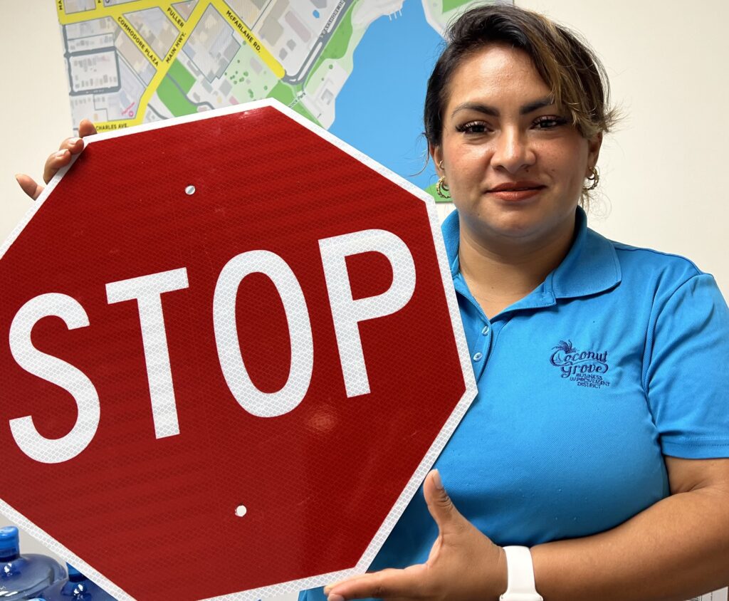 A lady wearing a blue shirt holding a red stop sign.