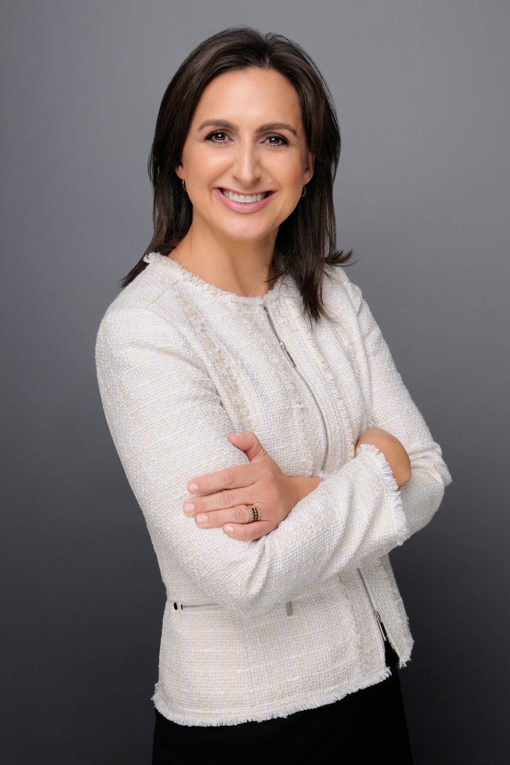 Lady wearing a white blouse with her arms folded.