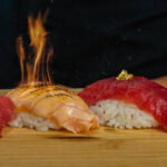 Sushi pieces on a wooden board topped with edible gold flakes and flames.