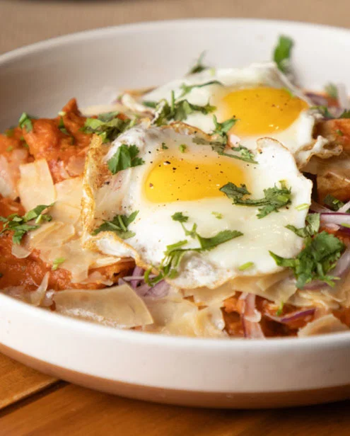 Brunch dish with fried eggs on top garnished with parsley.