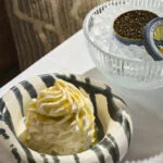 whipped dish drizzled with honey next to a bowl of iced opened caviar.