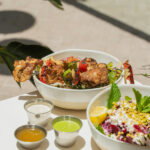 Grilled chicken with fresh salads, garnished with mint and lemon slices, from Avo Miami