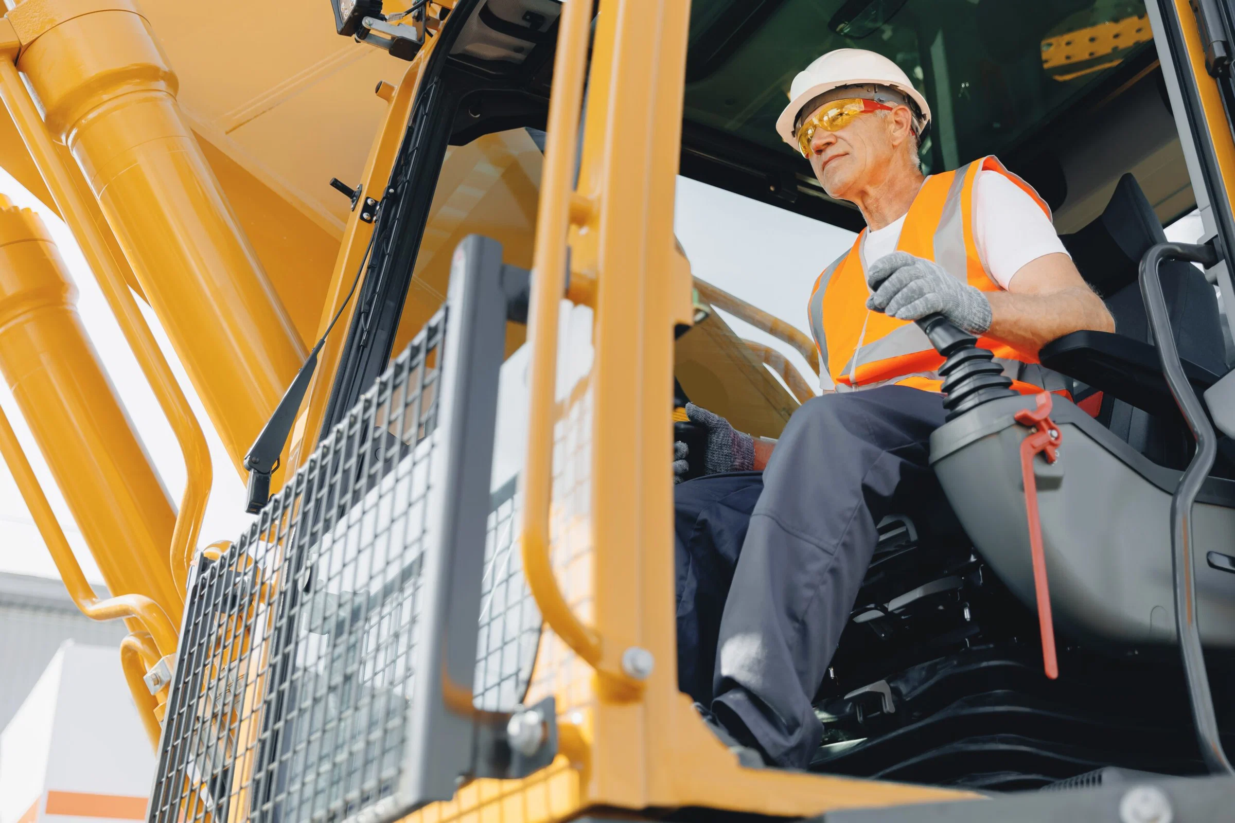 Man operating heavy machinery outdoors wearing safety equipment.