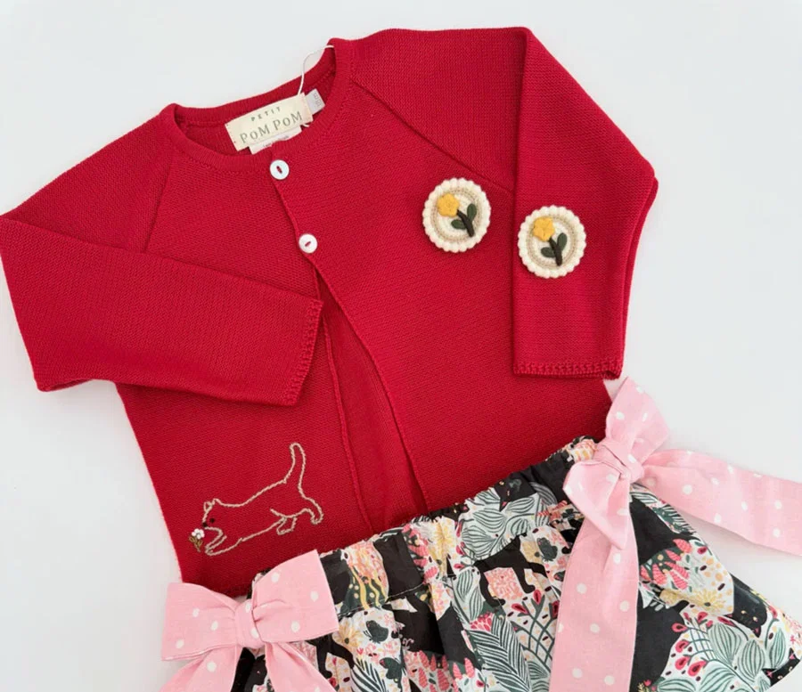 Red sweater with embellishments paired with a skirt with pink polka dot bows.
